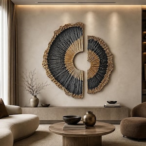 Op de afbeelding: Een grote, tweedelige wandsculptuur met een cirkelvormig ontwerp en een gestructureerd, stralend patroon. Het kunstwerk toont een opvallend contrast tussen diepzwarte en metallic gouden afwerkingen met grillige, organische randen.