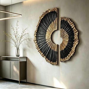 Op de afbeelding: Een tweedelige wandkunstset met cirkelvormige, waaiervormige figuren met een getextureerd, geplooid ontwerp. Het kunstwerk toont een opvallend contrast tussen diepzwarte en metallic gouden afwerkingen, gerangschikt in een gespleten compositie.