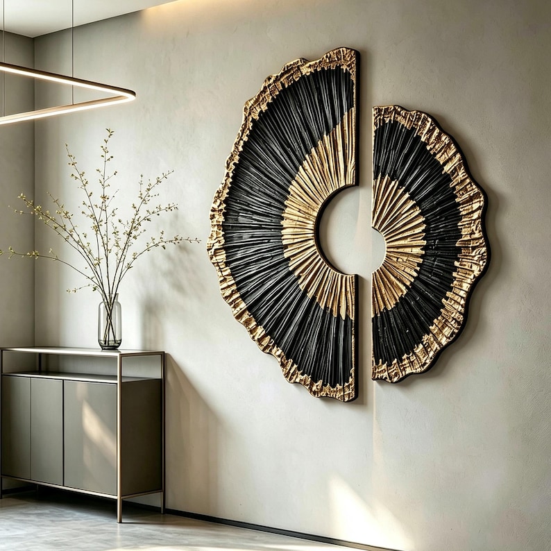 Op de afbeelding: Een tweedelige wandkunstset met cirkelvormige, waaiervormige figuren met een getextureerd, geplooid ontwerp. Het kunstwerk toont een opvallend contrast tussen diepzwarte en metallic gouden afwerkingen, gerangschikt in een gespleten compositie.