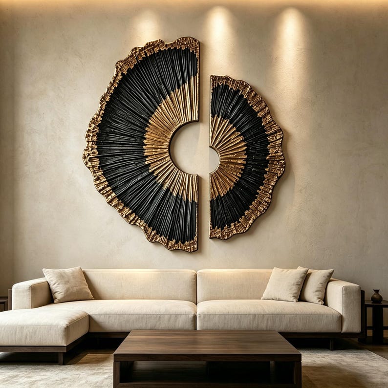 Op de afbeelding: Een groot tweedelig wandkunstobject met een cirkelvormig ontwerp en stralende lijnen. Het stuk is afgewerkt in een combinatie van matzwart en metallic goud, met getextureerde, onregelmatige randen die een waaiervormig, gelaagd uiterlijk cre&euml;ren.