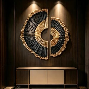 Op de afbeelding: Een tweedelige cirkelvormige wandsculptuur met een radiaal patroon van zwarte en gouden textuursegmenten. Het ontwerp bestaat uit een groter linkergedeelte en een kleiner rechtergedeelte, beide met een zonnestraaleffect en gouden randen.