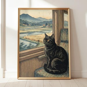Pode incluir: Uma impressão emoldurada com um gato preto olhando pela janela de um trem. O gato está sentado em um assento estampado, com uma paisagem de campos, água e montanhas visível através da janela. A obra de arte tem uma estética vintage de inspiração japonesa.