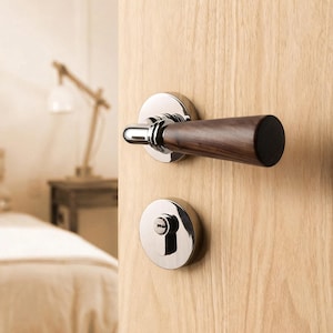 Peut inclure: Gros plan sur une porte avec une poignée moderne en chrome poli et une poignée en bois foncé. La porte comporte également un cache-serrure chromé assorti. La porte est en bois clair.
