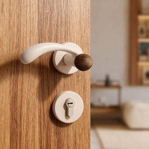 Puede incluir: Juego de manija y cerradura de puerta color crema sobre una puerta de madera. La manija tiene un diseño curvo con un acento de madera oscura. La cerradura tiene un ojo de cerradura y una placa circular a juego de color crema. La puerta es de madera clara.