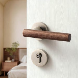 May include: A door handle set with a bronze finish and a cylindrical wooden handle. The set includes a round backplate and a keyhole, mounted on a white wooden door. The handle is a warm brown color.