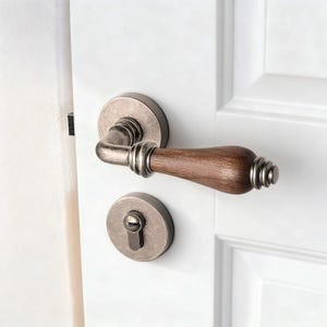 May include: A close-up of a door handle and lock set. The handle features a dark wood grip with a brushed metal finish. The lock is a matching brushed metal with a keyhole. The door is white.