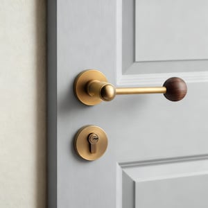 Könnte beinhalten: Messing-Türgriff-Set mit einem holzförmigen Kugelende. Der Griff und das Schlüsselloch sind an einer hellgrauen Tür angebracht. Die Türbeschläge haben ein modernes, minimalistisches Design.