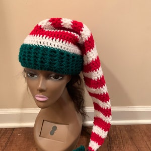 May include: A red, white and green striped elf hat with a long, pointed tip and a green pom-pom.