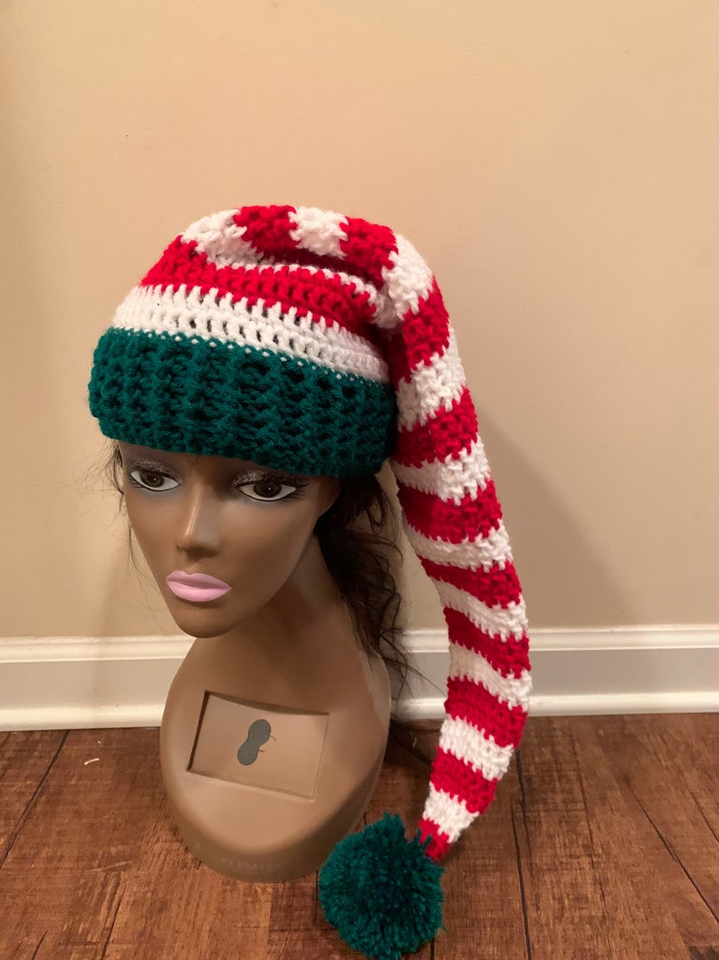 May include: A red, white and green striped elf hat with a long, pointed tip and a green pom-pom.