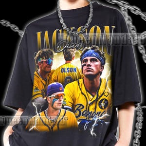 Peut inclure: T-shirt unisexe noir avec un graphisme de joueurs de baseball en uniformes jaunes et bleus. Le t-shirt porte l'inscription "Jackson Olson" en or. Le modèle porte une taille 2XL.
