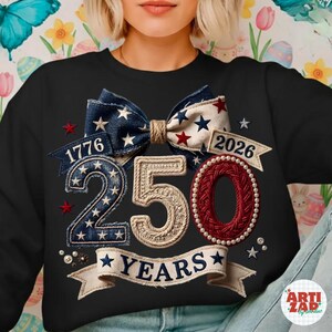 Puede incluir: Sudadera negra con un diseño patriótico que celebra 250 años. Presenta un lazo con estrellas y rayas, los números "250" en una fuente texturizada y los años "1776" y "2026" en pancartas. La palabra "YEARS" está en una pancarta.