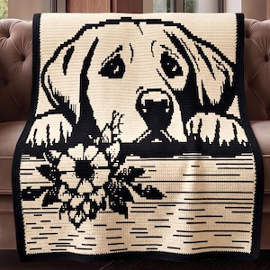 May include: A cream-colored crocheted blanket featuring a black and white image of a dog's face and paws, with a floral design at the bottom. The blanket is draped over a brown sofa.