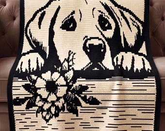 May include: A cream-coloured crocheted blanket featuring a black and white image of a dog's face and paws, with a floral design at the bottom. The blanket is draped over a brown sofa.