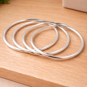 May include: A set of three ceramic mugs with a speckled, matte finish. The mugs are in shades of cream, light grey, and dark grey. Each mug has a simple, minimalist design, ideal for coffee or tea.