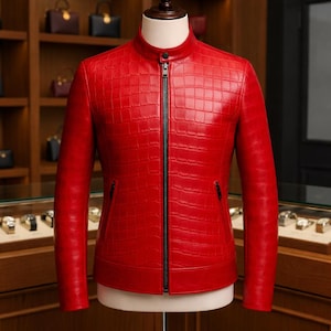 May include: A vibrant red leather jacket with a textured, crocodile-like pattern. The jacket features a stand-up collar, a full-length black zipper, and two small side pockets. The jacket is displayed on a mannequin.
