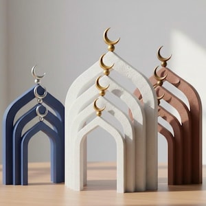May include: Three decorative arch-shaped sculptures in blue, white, and brown. Each features a crescent moon design at the top. The sculptures are arranged on a wooden surface, creating a minimalist and elegant aesthetic.