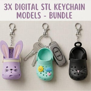 May include: Three novelty keychain models shaped like miniature clogs. They include a purple bunny, a teal clog with a sun, cloud, and heart, and a black cat clog. The keychains are attached to silver key rings.