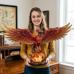 Può includere: Una scultura dettagliata di una fenice con le ali spiegate, con sfumature di rosso, arancione e oro. L'uccello mitico è appollaiato sopra un globo luminoso, tenuto da una persona. La scultura è un oggetto decorativo.