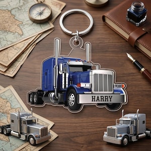 May include: A blue semi-truck keychain with the name "HARRY" on the front. The keychain is on a wooden surface with miniature semi-truck models and a compass. The keychain has a silver ring.