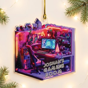 May include: A flat, square-shaped acrylic ornament featuring a detailed illustration of a gaming room with a computer, keyboard, and chair, illuminated by purple and pink neon lights. The text JOSHAN'S GAMING ROOM is printed in white on the front.