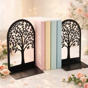 May include: Black metal tree design bookends holding pastel-colored books. The bookends have a cutout tree design and a rectangular base. The books are in shades of pink, yellow, and blue. The scene is decorated with flowers and petals.
