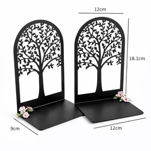 May include: Black metal tree-shaped bookends. Each bookend is 18.1 cm tall, 12 cm wide, and 9 cm deep, with a tree design cut out. Small pink flowers are attached to the base. The weight is 327g.