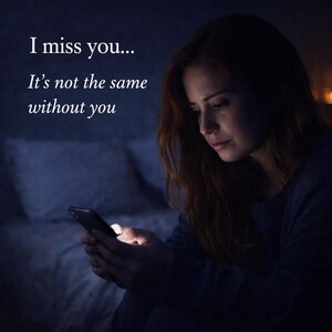 May include: A woman with long auburn hair looks down at a smartphone in a dimly lit room. The text "I miss you... It's not the same without you" is displayed in white font on the upper left of the image.