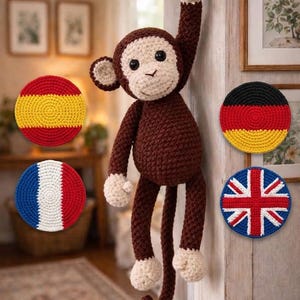 以下が含まれることがあります： フックに吊るされた茶色とクリーム色の編みぐるみのサルと、スペイン、ドイツ、フランス、イギリスの国旗柄をあしらった4枚の円形のかぎ針編みのコースターが、室内の背景に配置されています。