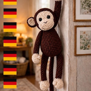 May include: A crocheted monkey toy with dark brown yarn for the body, limbs, and long tail, and cream-colored yarn for the face, ears, hands, and feet. The monkey has black plastic eyes and a stitched nose and mouth, hanging from a metal wall hook.