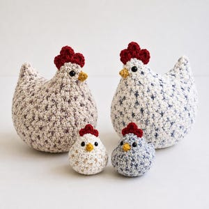 May include: Four crocheted chicken ornaments in different sizes. Two larger chickens have speckled white and beige bodies, red combs, yellow beaks, and black eyes. Two smaller chickens are white and blue, with red combs, yellow beaks, and black eyes.
