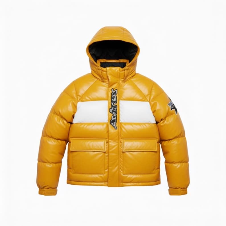 May include: Mustard yellow puffer jacket with a hood and two front pockets. The jacket features a white stripe across the chest with the brand name in black. A small logo is on the upper left sleeve. The jacket is designed for cold weather.
