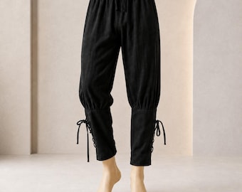 May include: Black trousers featuring an elasticized waistband with a drawstring closure. The pants have a relaxed fit through the upper legs and taper toward the calves, where they are secured with side lacing details and tied ribbons.