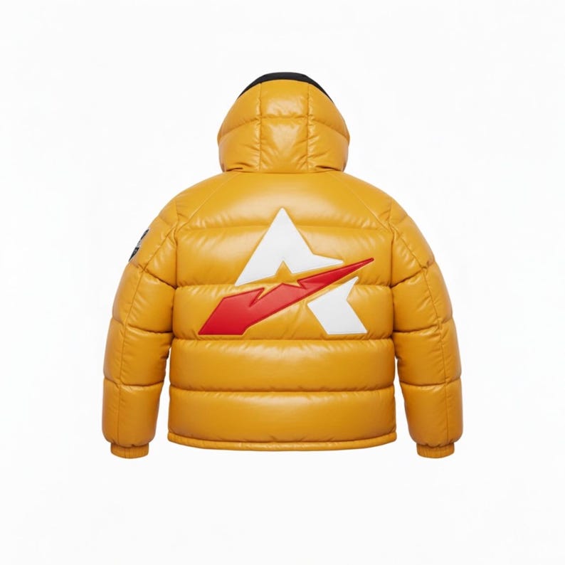 May include: Mustard yellow puffer jacket with a hood. The back of the jacket features a white and red logo. The jacket has a black hood lining and a small patch on the left sleeve. The jacket is designed for cold weather.