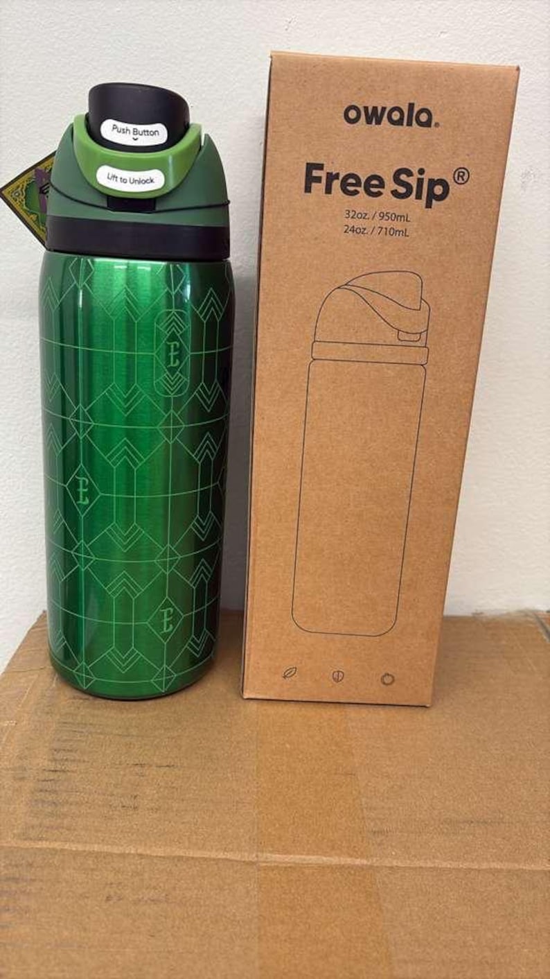 May include: A green Owala Free Sip water bottle with a geometric pattern and a black and green lid. The bottle is 32oz / 950mL. The box next to it has the words "Free Sip" and a drawing of the bottle.