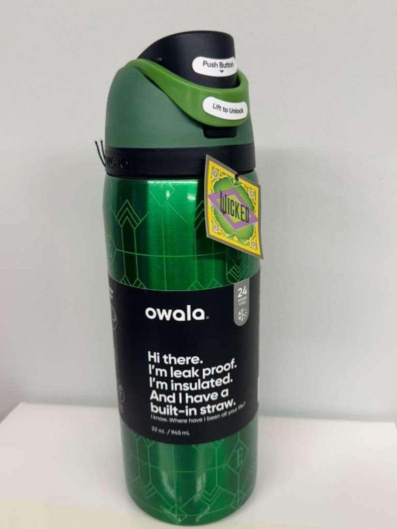 May include: Green Owala water bottle with a black lid and a green handle. The bottle has a geometric pattern and the word "WICKED" on a tag. Text on the bottle reads "Hi there. I'm leak proof. I'm insulated. And I have a built-in straw."