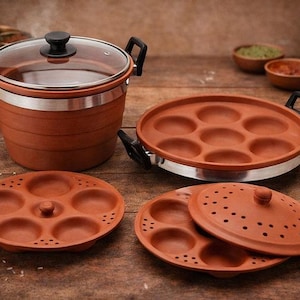 Puede incluir: Un juego de cocina de color terracota con una olla con tapa de cristal, dos bandejas redondas con hendiduras circulares y dos tapas. El juego está diseñado para cocinar al vapor o cocinar, ideal para la cocina india tradicional.
