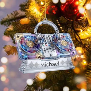 Könnte beinhalten: Ein dekoratives Ornament in Form eines DJ-Mischpults mit aufliegenden Kopfhörern. Das Mischpult verfügt über ein buntes Buntglasmuster auf den Plattentellern, ein zentrales Bedienfeld und einen Sockel mit dem aufgedruckten Namen Michael.