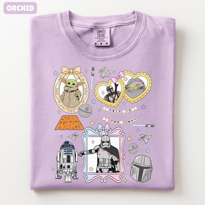 Puede incluir: Camiseta de color orqu&iacute;dea con personajes y gr&aacute;ficos de Star Wars. El dise&ntilde;o incluye im&aacute;genes de Grogu, el Mandaloriano y otros elementos ic&oacute;nicos, con el texto "THIS IS THE WAY".
