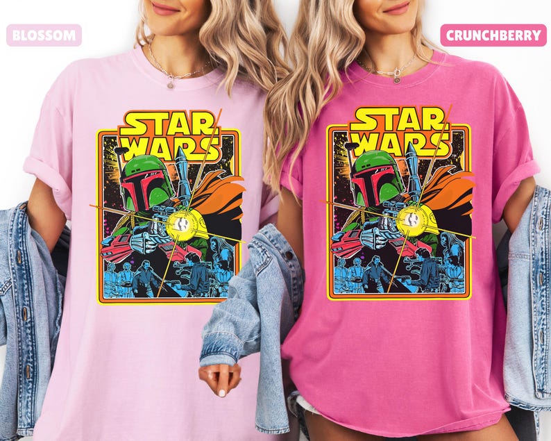 May include: Two t-shirts, one light pink and one fuchsia, each featuring a vintage Star Wars graphic. The graphic includes the words "STAR WARS" in yellow, and an illustration of Boba Fett. The shirts have short sleeves.