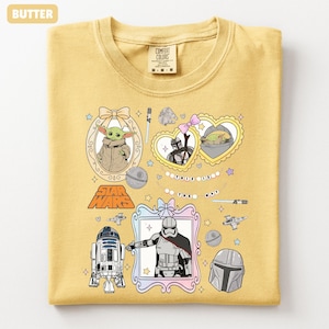 Puede incluir: Camiseta de cuello redondo de color mantequilla con personajes y gr&aacute;ficos de Star Wars. El dise&ntilde;o incluye im&aacute;genes de Grogu, R2-D2 y el texto "This is the Way". La camiseta est&aacute; hecha de un material suave y tiene una etiqueta Comfort Colors.