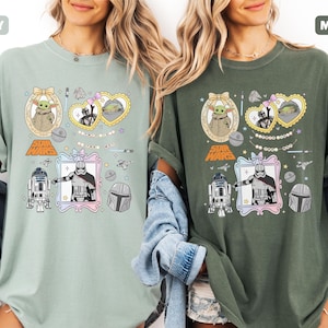 Puede incluir: Dos camisetas, una en verde bah&iacute;a y otra en verde musgo, cada una con gr&aacute;ficos de Star Wars. Los dise&ntilde;os incluyen personajes como Grogu, Darth Vader y R2-D2, enmarcados en elementos decorativos. El logo de Star Wars tambi&eacute;n es visible.