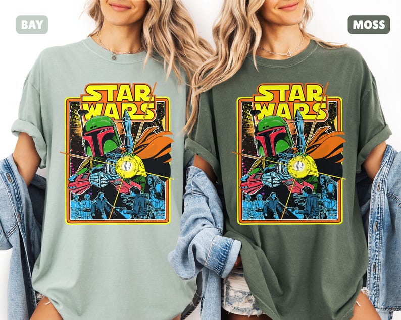 May include: Two t-shirts, one in bay and one in moss, each featuring a Star Wars graphic. The graphic includes the text "STAR WARS" in yellow, and an illustration of Boba Fett. The shirts are short-sleeved.