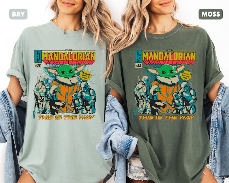 May include: Two t-shirts, one in bay and one in moss, featuring a comic book style graphic. The graphic includes the text "THE MANDALORIAN" and "THIS IS THE WAY", along with an illustration of Grogu and other characters.