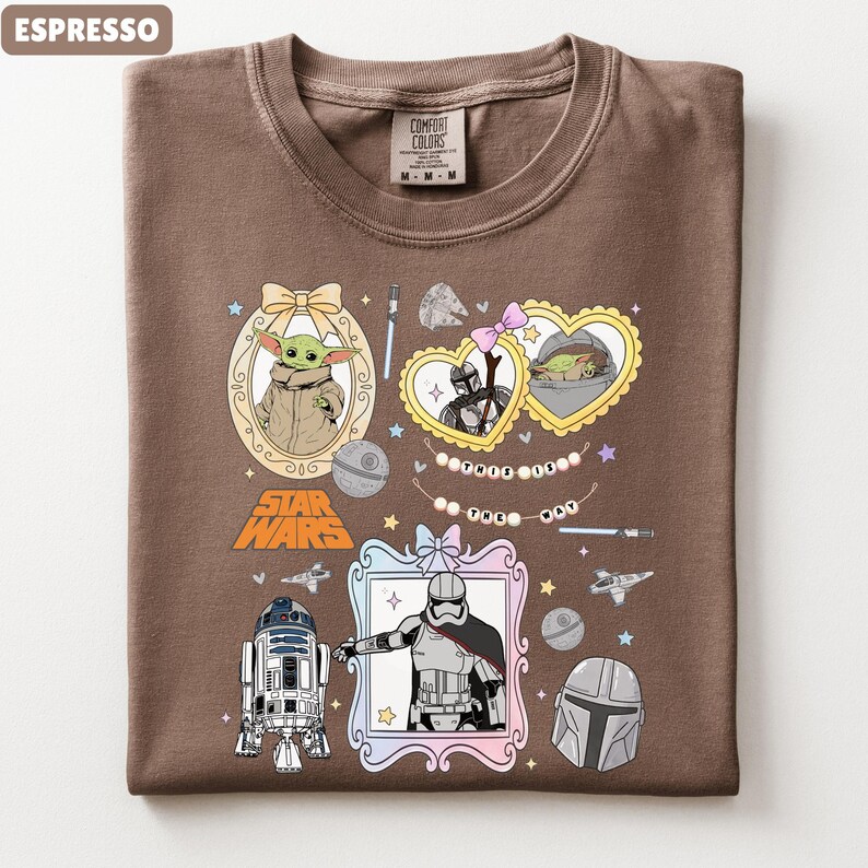 Puede incluir: Camiseta color espresso con personajes y elementos de Star Wars. El dise&ntilde;o incluye a Grogu, R2-D2, Stormtroopers y el logo de Star Wars. La camiseta tiene cuello redondo y una etiqueta Comfort Colors.