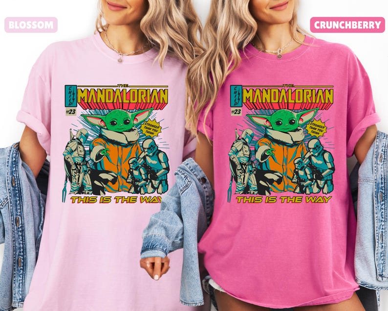 May include: Two t-shirts, one light pink and one hot pink, featuring a comic book style graphic. The graphic includes the text "The Mandalorian" and "This is the Way", along with an image of Grogu and other characters.