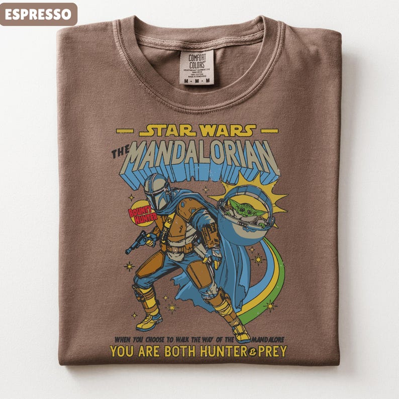 以下が含まれることがあります： スターウォーズのマンダロリアンが描かれたエスプレッソカラーのTシャツ。デザインにはマンダロリアン、グローグー、そして「YOU ARE BOTH HUNTER & PREY」というテキストが含まれています。このシャツはクルーネックで、Comfort Colorsのタグが付いています。