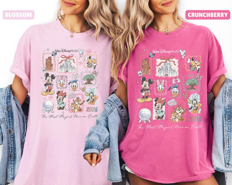 May include: Two t-shirts, one light pink and one fuchsia, featuring a colorful graphic design. The design includes various Disney characters and landmarks, with the text "Walt Disney World" and "2026". The phrase "The Most Magical Place on Earth" is also present.
