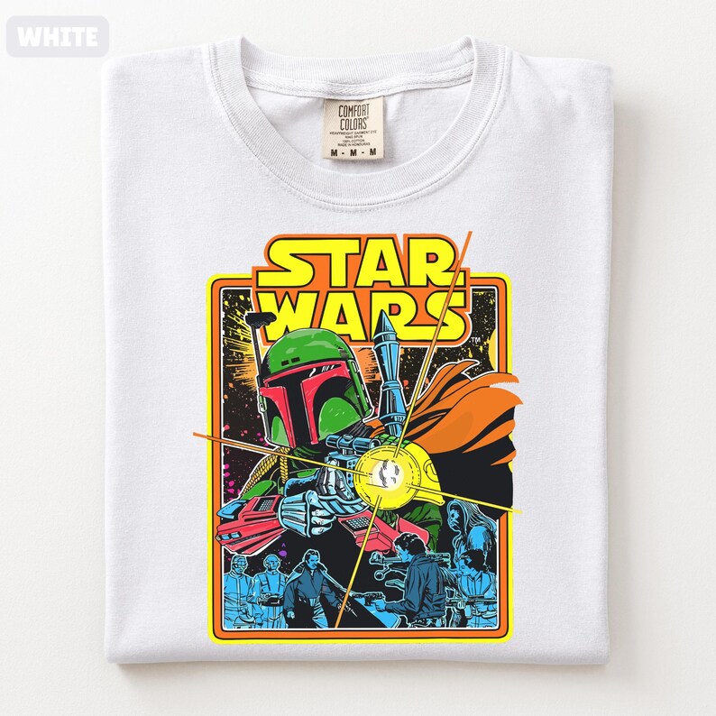 May include: White t-shirt featuring a Star Wars graphic. The design includes a colorful illustration of Boba Fett, with the Star Wars logo in yellow and orange. The shirt is a Comfort Colors brand.