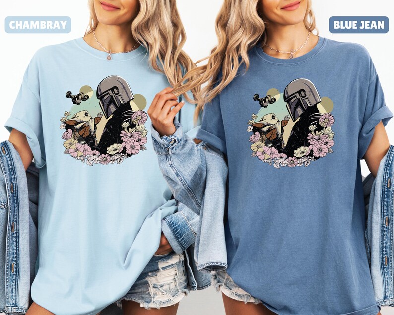 May include: Light blue and blue jean t-shirts featuring a graphic of a character in a helmet with a baby character surrounded by flowers. The text "CHAMBRAY" and "BLUE JEAN" are above the shirts.