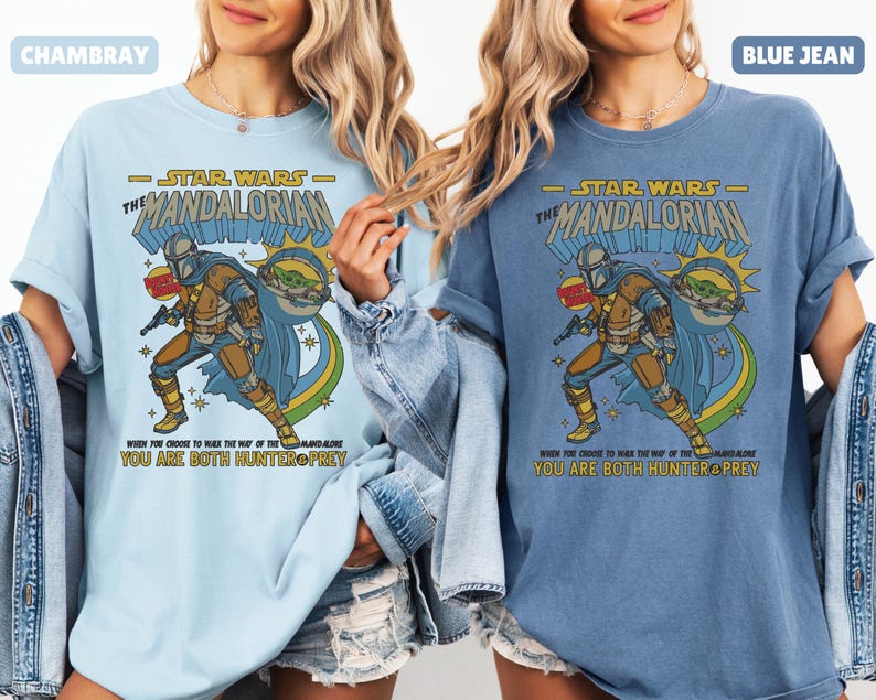 以下が含まれることがあります： スターウォーズのマンダロリアンデザインのライトブルーとブルージーンズのTシャツ。デザインにはマンダロリアンとグローグーが含まれており、「WHEN YOU CHOOSE TO WALK THE WAY OF THE MANDALORIAN, YOU ARE BOTH HUNTER & PREY」というテキストがあります。